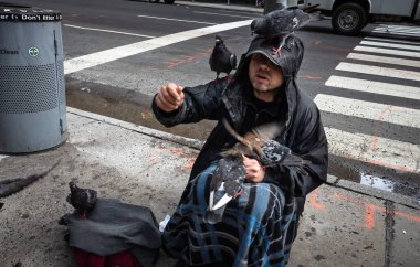 New York, ABD - Eyl 24, 2018: Manhattan sokak sahne. Kuşlar ve Güvercin besleyen evsiz bir adam