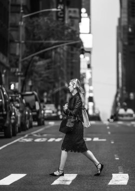 New York, ABD - 04 Mayıs 2016: akşam saat sahnede Manhattan street siyah beyaz görüntü. Genç kadın sokak ve dinleme müzik kulaklık ile geçiş