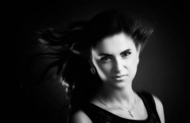 Siyah beyaz portre koyu arka plan üzerinde uçan bulanık saçlı güzel bir genç kadının