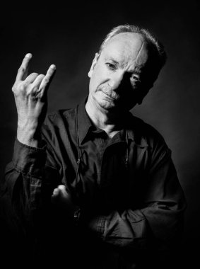 Siyah ve beyaz koyu arka plan üzerinde el hareketi yaşlı bir adam portresi. Yaşlı ihtiyar parmak boynuzları ile gösterir. Boynuzları rock işareti sembol jest. Yaşam tarzı kavramı