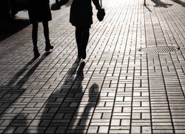 Yaşam tarzı kavramı. Işık ve gölge City. Büyük bir şehrin sokaklarında yürüyüş ve arka ışık tarafından insan siluetleri. Gölgeler akşam ışığında street yürüyüş insanların.