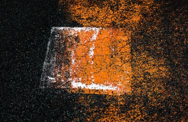 Asfalt üzerinde soyut renkli kompozisyon. Soyut işareti asfalt zemin üzerine. Doku turuncu ve beyaz lekeler, eski kırık asfalt yüzey deseni ile yol asfalt yakın çekim