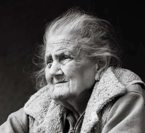 Old age and lifestyle concept. Black and white portrait of a very old and tired wrinkled woman outdoors. Very old hoary woman face closeup portrait. Aging process - very old senior women