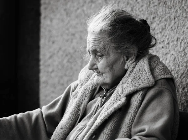 Old age and lifestyle concept. Black and white portrait of a very old and tired wrinkled woman outdoors. Very old hoary woman face closeup portrait. Aging process - very old senior women