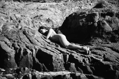 Plajda çıplak kız tans. Genç çıplak kadın kil cliff sahil üzerinde yatıyor. Siyah beyaz resim
