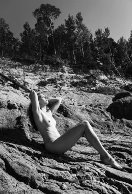 Plajda çıplak kız tans. Genç çıplak kadın kil cliff sahil üzerinde yatıyor. Siyah beyaz resim