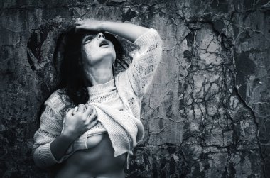 Yaşam tarzı kavramı. Koyu mavi makamı tek renkli görüntüde. Eski beton duvar arka plan karşı bir ceket ile çıplak kadın