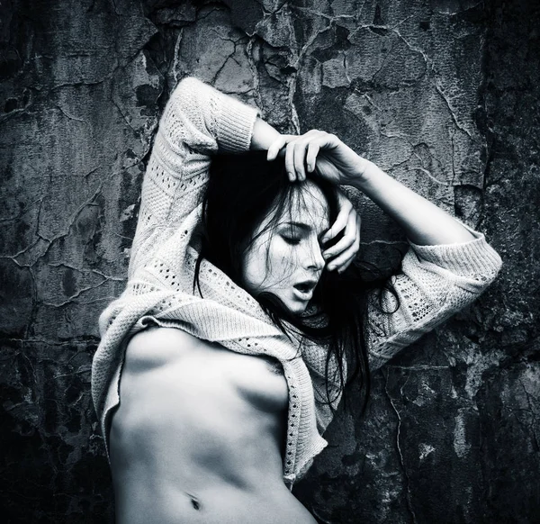 Yaşam tarzı kavramı. Koyu mavi makamı tek renkli görüntüde. Eski beton duvar arka plan karşı bir ceket ile çıplak kadın