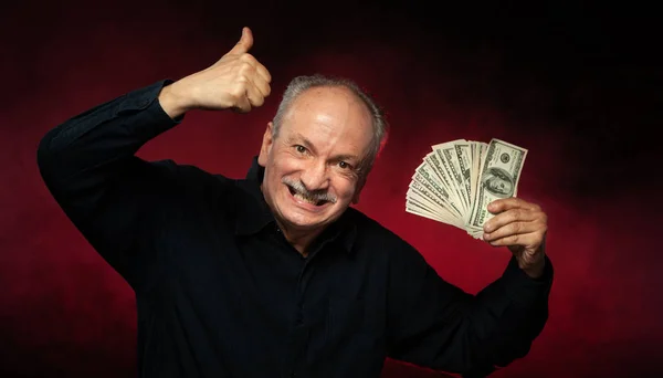 上級紳士お金のスタックを保持します 興奮して古いビジネスマンの肖像画 濃い赤の背景にドル紙幣を持って幸せな老人 — ストック写真