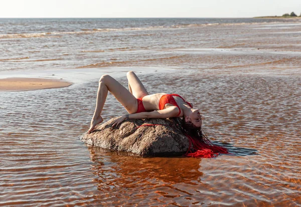 Meisje in een rode badpak op het strand — Stockfoto