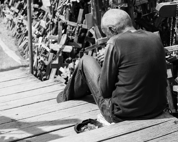 Un mendigo se sienta cerca de una gorra con monedas — Foto de Stock