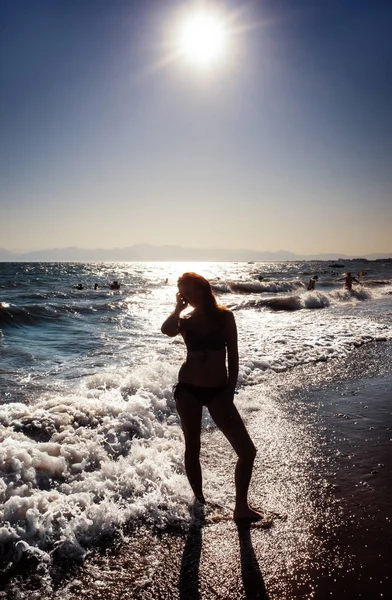 Okyanus dalgalarında gün batımında duran kadın — Stok fotoğraf
