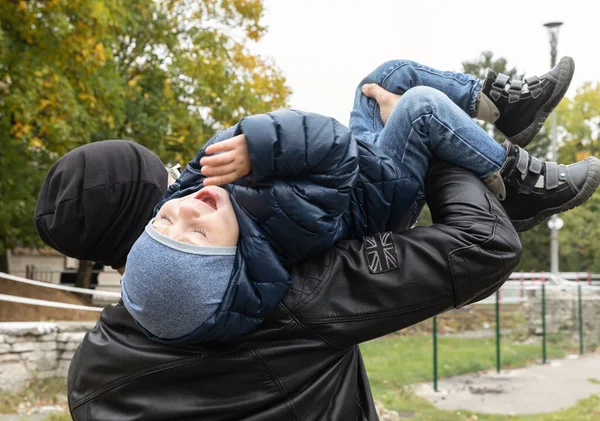 快乐生活的概念 秋天的一天 年轻的爸爸背着一个快乐的两岁儿子在公园里 — 图库照片