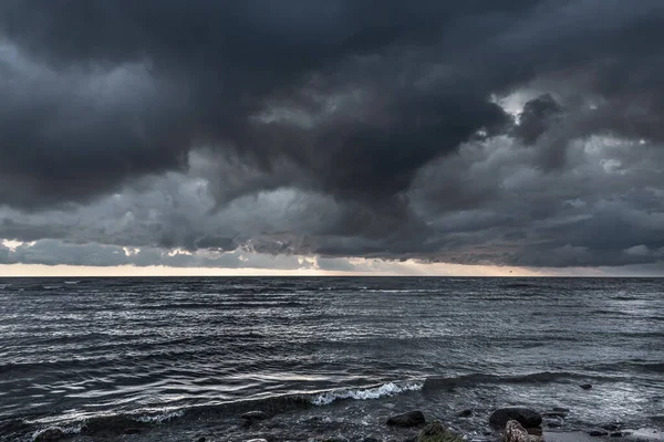 Amazing dramatic landscape. Dramatic dark clouds during sunset at sea. Dark sea water and heavy beautiful grey clouds.