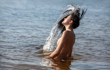 Suda Eğlence Kızları. Aktif, genç, çıplak bir kadın saçlarını sallayarak içeri su sıçratıyor. Güzel, sağlıklı bayan rahatla. Hareketi durdur