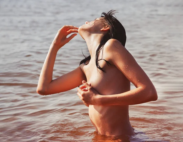 Doğanın tadını çıkaran güzel bir kız. Sahilde poz veren genç bir kız. Denizde çıplak bir kadın