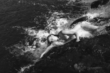 Güzellik, nüdizm ve sağlıklı yaşam tarzı konsepti. Güneşli bir yaz gününde çıplak bir kadın. Genç bir kadın şelalede tazeliğin ve temiz suyun tadını çıkarıyor. Genç ve güzel bir kadın nehirde yıkanıyor.