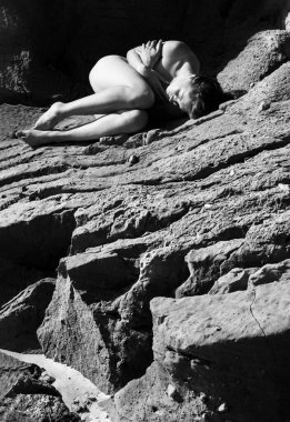 Plajda çıplak kız bronzlaşması. Kumtaşında çıplak genç bir kadın