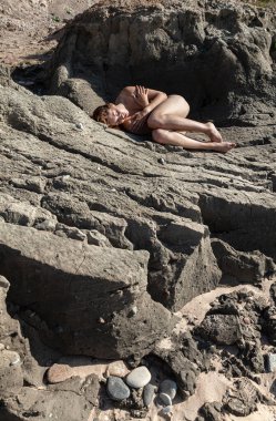 Plajda çıplak kız bronzlaşması. Kumtaşında çıplak genç bir kadın