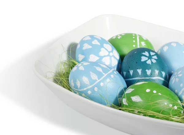 Beyaz plaka üzerinde mavi ve yeşil Paskalya yortusu yumurta — Stok fotoğraf