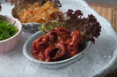 Bebek ahtapot, deniz yosunu ve denizanası masada kesilmiş buz üzerinde Japonca terbiyeli 