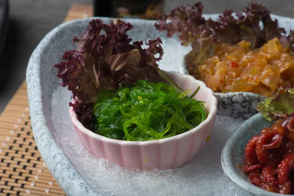 Bebek ahtapot, deniz yosunu ve denizanası masada kesilmiş buz üzerinde Japonca terbiyeli 