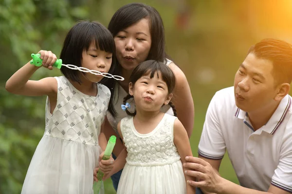 娘と屋外の公園でシャボン玉遊びで遊んで幸せな若いアジア家族 — ストック写真