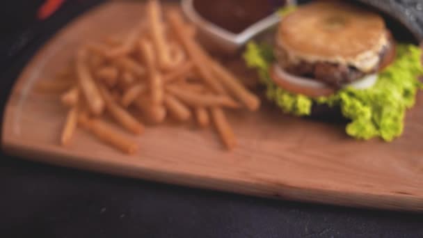 在木制切菜板上的汉堡与薯条的特写镜头 — 图库视频影像
