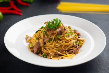  close-up shot of spaghetti with iberico pork on black