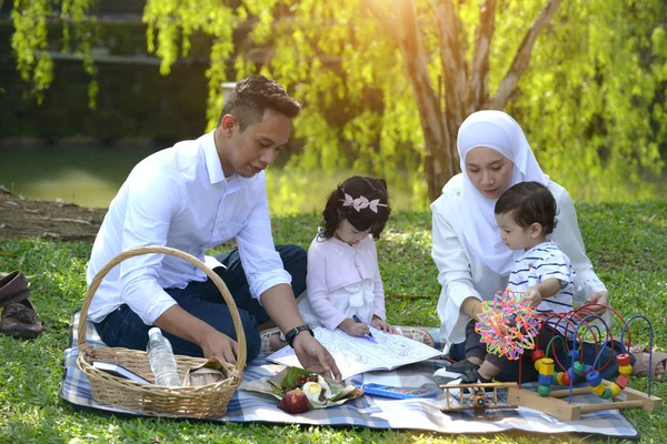 asian father and mother studying with kids together in park