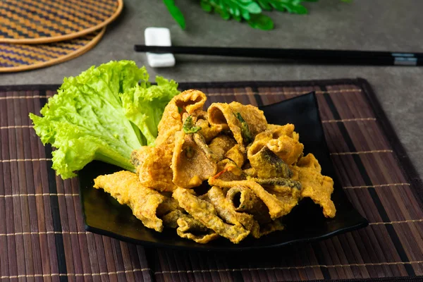Crispy fried fish Skin with salted egg on black plate