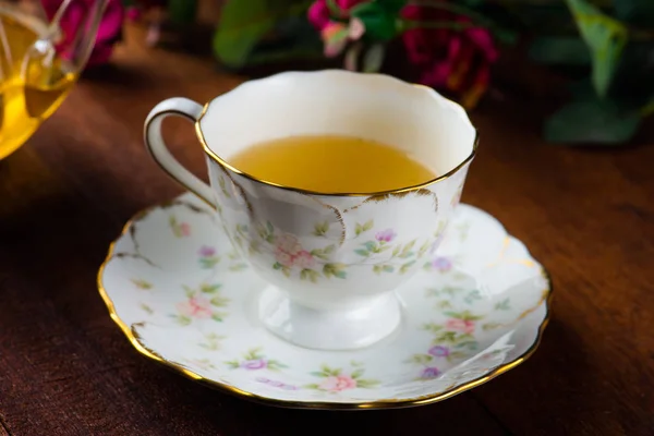 ピンクの花と木製のテーブルの上のお茶のカップのクローズ アップ撮影 — ストック写真