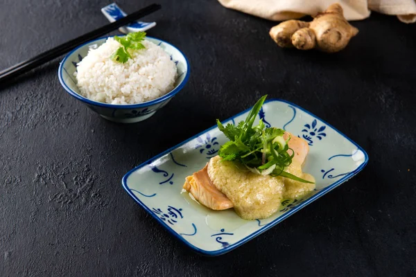chinese style ginger steamed fish with rice on black surface