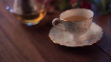 pembe çiçeklerle ahşap masa üzerinde cam çaydanlık ve çay fincan yakın çekim görüntüleri