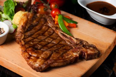 Otlar, domates ve tuz ile süslenmiş ızgara büyük t-kemik biftek yakın çekim 