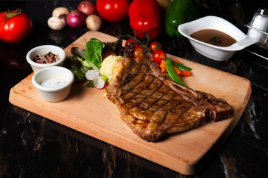 Otlar, domates ve tuz ile süslenmiş ızgara büyük t-kemik biftek yakın çekim 