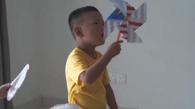 evde kağıt rüzgar değirmeni ile sevimli asya çocuk