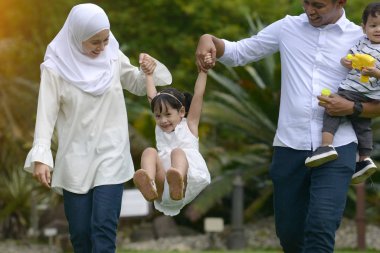 Asya aile birlikte parkta kamera bakarak gülen
