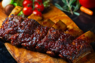 Barbekü sığır kaburga biftek eski vintage ahşap kesme tahtası üzerinde acı biber ve taze domates ile servis