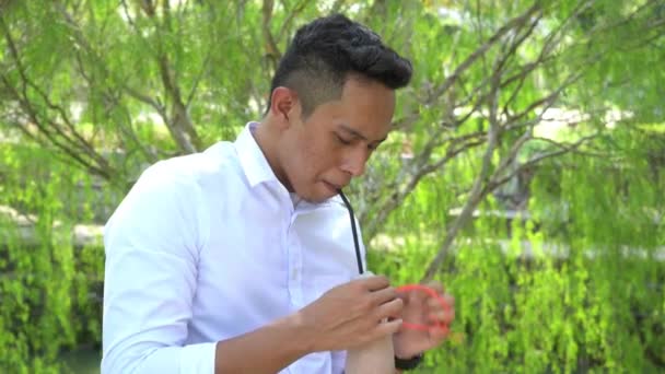 若いアジア系男性がストローでビニール袋から酒を飲んでいる映像です — ストック動画