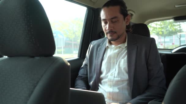 ハンサムなアジア系ビジネスマンが車のノートパソコンで — ストック動画