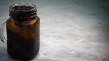 Mason kavanozundaki buzlu çay ve gri arka plandaki yakın çekim görüntüleri.
