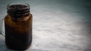 Mason kavanozundaki buzlu çay ve gri arka plandaki yakın çekim görüntüleri.
