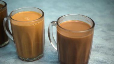 Kupalarda süt olan çay mı yoksa gri arka planda Teh Tarık olarak bilinen çay mı?