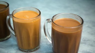 Kupalarda süt olan çay mı yoksa gri arka planda Teh Tarık olarak bilinen çay mı?