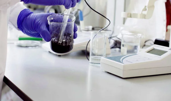 Mãos de um cientista que mede o pH da amostra — Fotografia de Stock