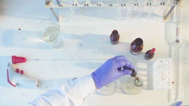 Mãos de um cientista a deixar cair um reagente em frascos — Vídeo de Stock