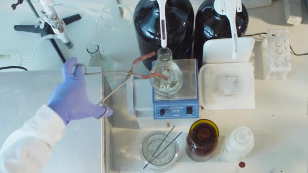 Hands place the flask on the magnetic stirrer — Stock Video