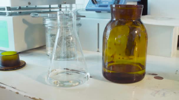 Mains d'un scientifique larguant un réactif dans une fiole 