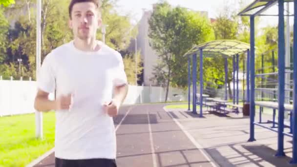Чоловік біжить по шляху для бігунів на стадіоні — стокове відео